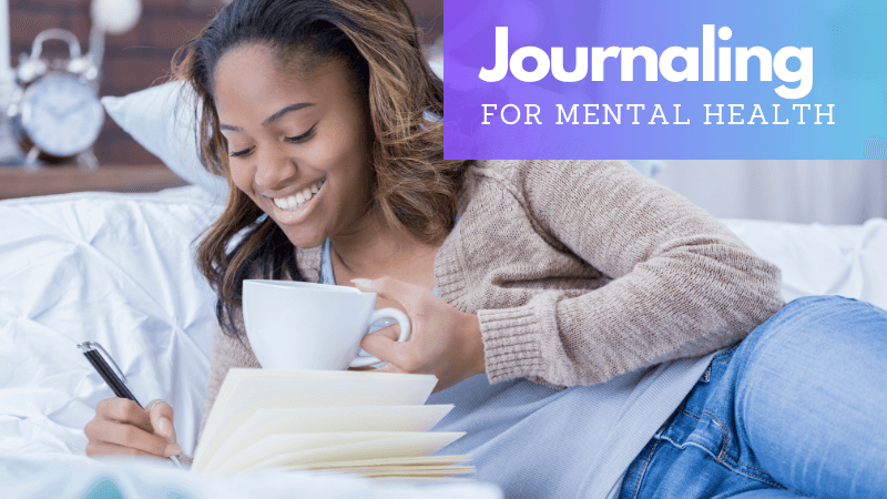 Young woman smiling while journaling in bed with a cup of coffee, depicting the therapeutic practice of journaling for mental health.